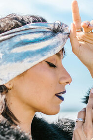 A woman wearing several rings and earrings, eyes closed