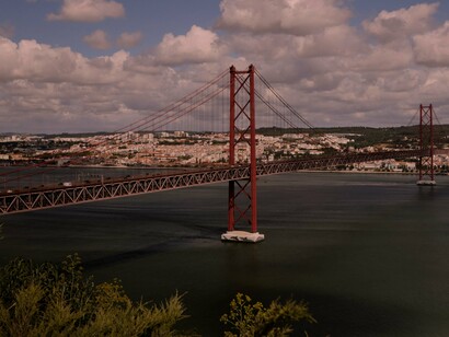 Ponte 25 de Abril em Lisboa, Portugal. A promessa de prosperidade económica raramente reflete nas condições de trabalho ou nos salários dos portugueses. Além disso, a falta de oportunidades para os jovens, especialmente para aqueles com formação académica, é uma das maiores dificuldades do país. A “falsa potencialidade” torna-se clara quando vemos que, apesar de tantas promessas de um futuro melhor, a maioria das pessoas não vê essas promessas materializarem-se, criando um ciclo de expectativas frustradas