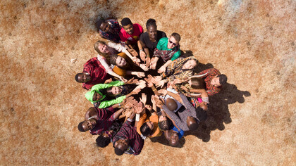 People joining hands and looking upward, diverse groups embracing, helping one another, and engaging in social inclusion activities