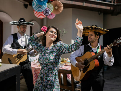 A woman in a dress dances as men wearing sombreros accompany her on guitars