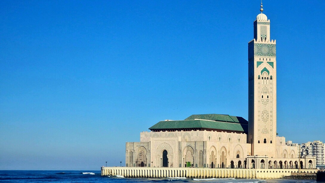 Morocco's Hassan II Mosque, set against a blue sky, representing the country's dedication to preserving its traditional architecture and design
