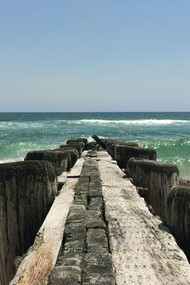A weathered pier stretches into the Atlantic along North Carolina’s untamed coast, where history and natural beauty meet