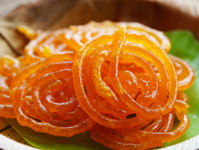 After frying, the jalebi is soaked in sugar syrup, giving it a crispy texture with a sweet, sticky coating