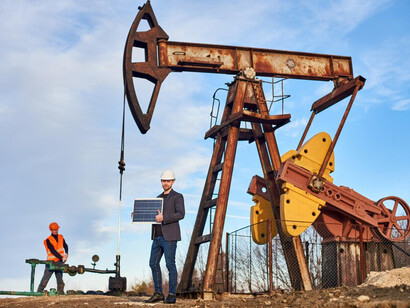 Engineers overseeing the pump jack’s operation in the oil field on a bright, sunny day