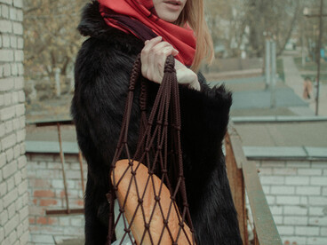 A woman in a black fur coat holding a loaf of bread in a Soviet city, Russia