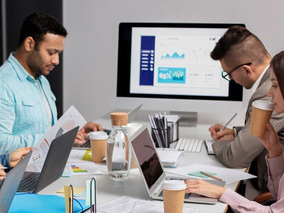 People working in the office with computers, analyzing real estate data visualizations and property market analytics, powered by AI technology