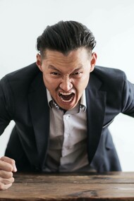 A man not managing his stress levels to the point where he's pounding on the table with anger