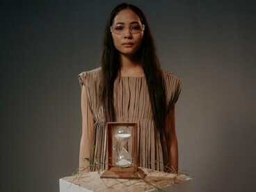 A woman behind an hourglass, mirroring the idea that aging is no longer an unstoppable countdown