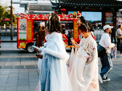 Using cell phones while wearing traditional Chinese clothes, the women proudly merge China's cultural heritage with modern times