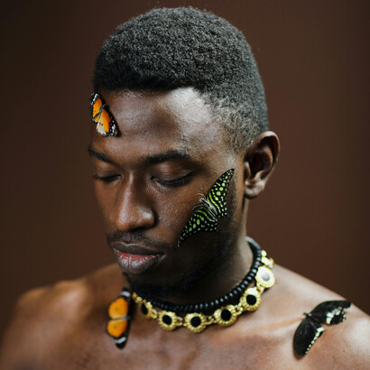 A poetic environmental portrait of a topless man surrounded by butterflies, symbolizing peaceful coexistence and harmony with nature