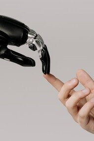 A human hand and a sleek black robot hand draw near to one another, symbolizing the convergence of human ingenuity and artificial intelligence