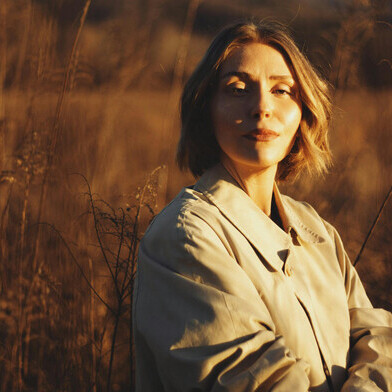 In the gentle glow of a Brevard sunset, a woman stands in a golden autumn field, wrapped in quiet light, US