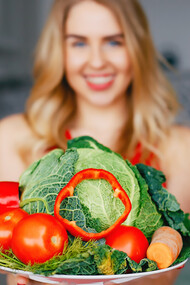 Capture the essence of a healthy lifestyle with an image of a sports girl in a kitchen surrounded by vibrant fruits and vegetables, embodying the principles of a plant-based diet and promoting longevity