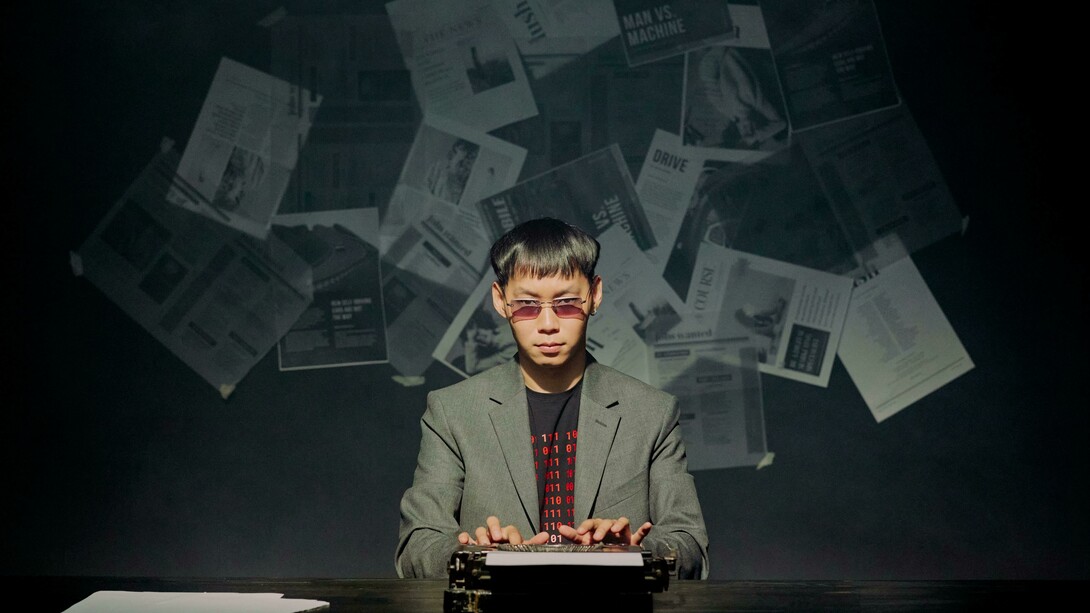 A journalist at a typewriter, staring at the camera as scattered newspapers fly behind him, symbolizing the chaos of the news cycle