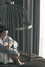 A woman practicing self-restraint lies in a bed cage, demonstrating control in a confined space