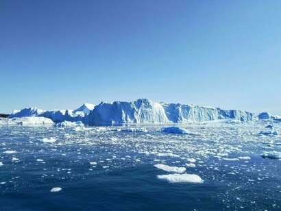Glacial ice loss is evident in the iceberg’s reduced mass and fragmentation within surrounding waters
