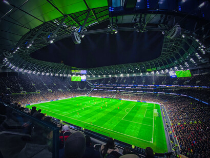 Le Tottenham Hotspur Stadium à Londres au Royaume-Uni, rayonne sous les projecteurs pendant un match nocturne, avec une architecture moderne et une atmosphère captivante