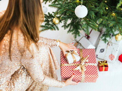 A woman setting Christmas presents in place, representing the anticipation and joy shared by families worldwide