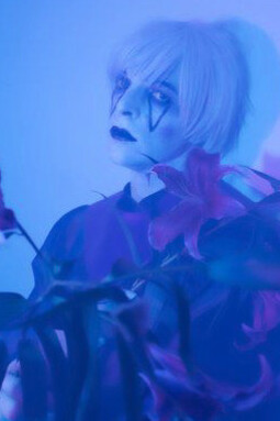 Shrouded in an atmospheric purple hue, the solitary figure of Drab Majesty evokes the haunting beauty of devotion and transformation