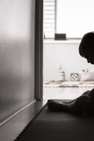 A child sits on the floor, their expression one of sadness and despair