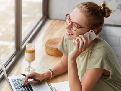 Focused woman with glasses in a café, using her laptop to draft text with help from an AI tool