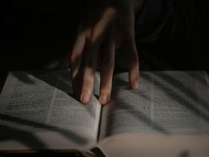A reader holding a book of simple religious praises