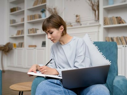 A woman learning from home, using technology to attend a Zoom lecture for her online course