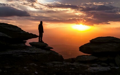 La sagoma di un uomo che si affaccia su un paesaggio al tramonto