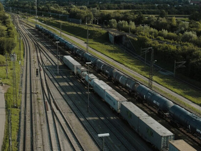 A long freight train crosses the scenic countryside, symbolizing the vital rail connection between Europe and Asia