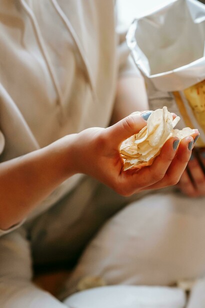 Female hands gripping a packet of crisps, representing processed food consumption and unhealthy eating habits