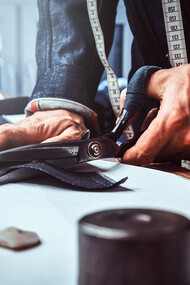 A craftsmen portraying precision and detail tailoring a Loro Piana suite