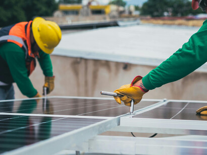 Worker fitting solar panels onto a house roof