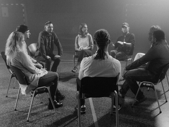 Grayscale photo of people sitting on chairs during a group therapy session