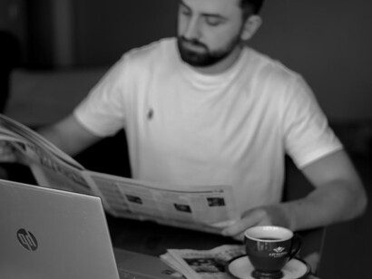 A man at a desk, absorbed in a newspaper, pondering the intersection of AI, journalism, and the evolving nature of truth in the digital age