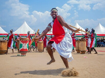 A Burundian performer dancing in traditional costume before ceremonial drums, symbolizing the strength of cultural traditions 