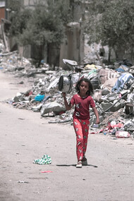 Una niña camina por las calles de la destruida Gaza en busca de comida