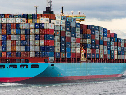 A cargo ship rests at the dock in a busy harbour under daylight