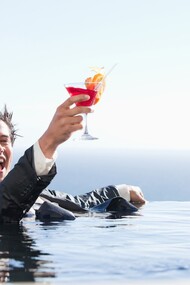 Un ejecutivo bañándose vestido y disfrutando de un cóctel