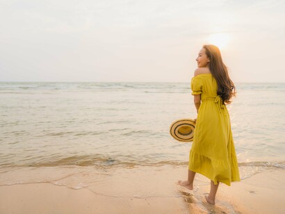 A woman watching the sunset by the shore, illustrating the gentle pause that travel sometimes offers