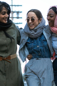 Amigas de diferentes nacionalidades caminham em direção à uma marcha em celebração ao dia da mulher