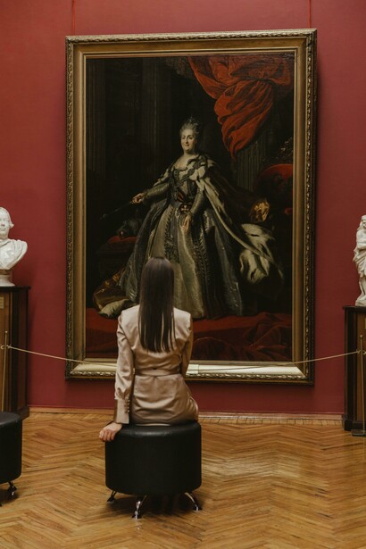 Back view of a woman sitting on a chair and looking at a painting