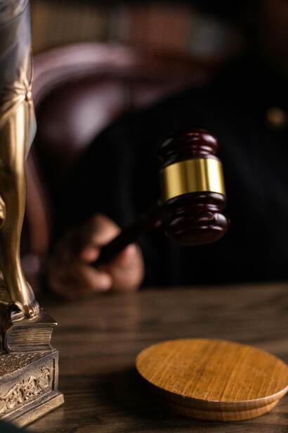 Someone grips a gavel, representing authority, law, and justice