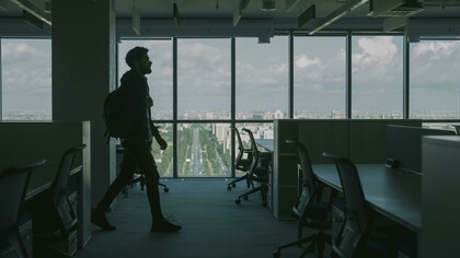 A man in a black jacket walking through an empty office
