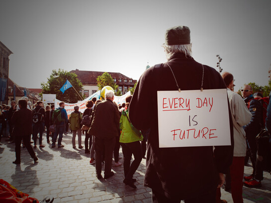 Man holding a banner reading “Every Day Is Future” during a protest