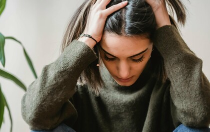 Une femme tenant sa tête dans la frustration, la douleur et la colère, probablement coincée dans une difficulté