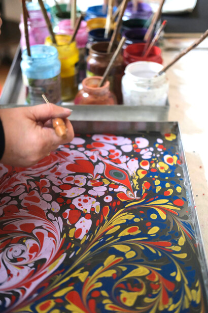 Colorful Ebru art in progress, with paints and tools in a bright, creative workspace filled with natural light