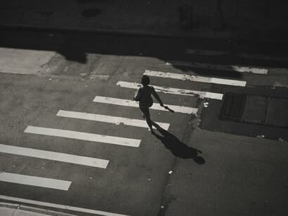 Un autre piéton marche dans la rue, symbolisant la lutte quotidienne des Bamakois pour se déplacer alors que le carburant se fait de plus en plus rare, mettant en lumière l'impact de la crise sur les déplacements urbains