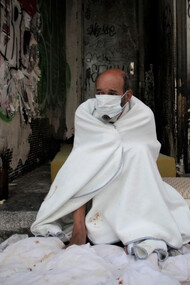 Una persona sin hogar descansa en el portal de un edificio abandonado, España