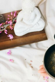 A person preparing to play a Tibetan singing bowl, surrounded by elements of mindfulness and meditation