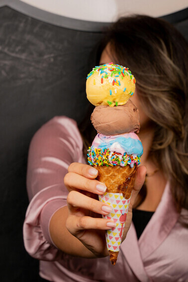 A woman’s hand holding an ice cream cone topped with sugar sprinkles